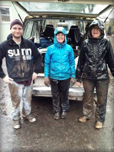 Three volunteers standing in rain