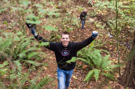 Volunteer in the forest with both arms raised and smiling
